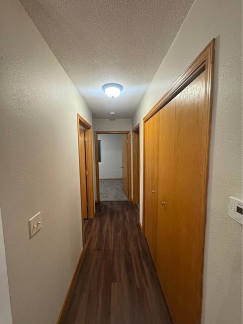 A long hallway with wood floors and white walls.