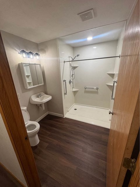 A small bathroom with a toilet, sink, and shower.