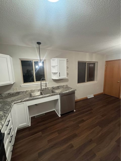 A kitchen with white cabinets and a marble countertop.