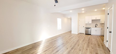 A spacious kitchen with white cabinets and a wooden floor.