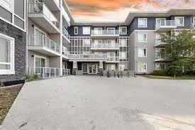 A large, multi-story residential building with balconies and a driveway in front.