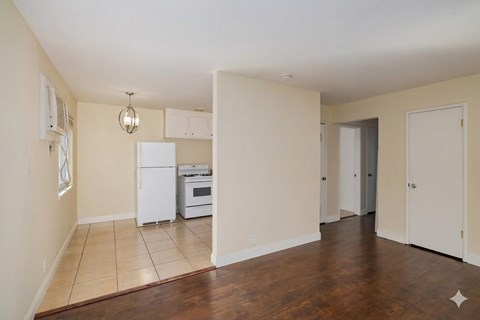 A kitchen with white appliances and a wooden floor.