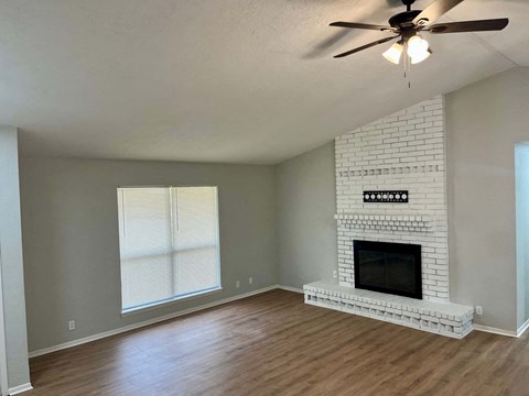 A living room with a fireplace and a ceiling fan.
