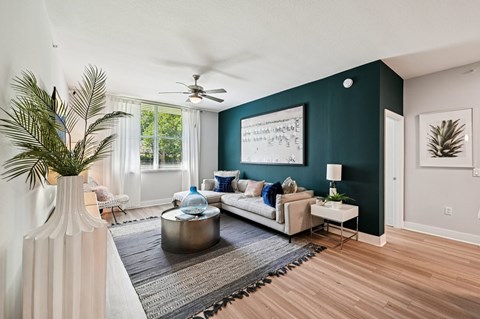 A living room with a white sofa, a coffee table, and a painting on the wall.