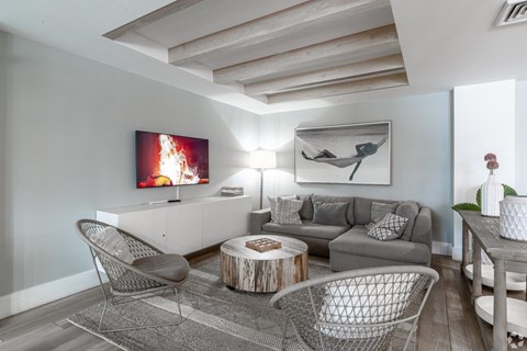 A living room with a grey couch, a coffee table, and a painting on the wall.