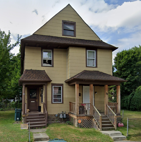 A small house with a brown roof and a porch.