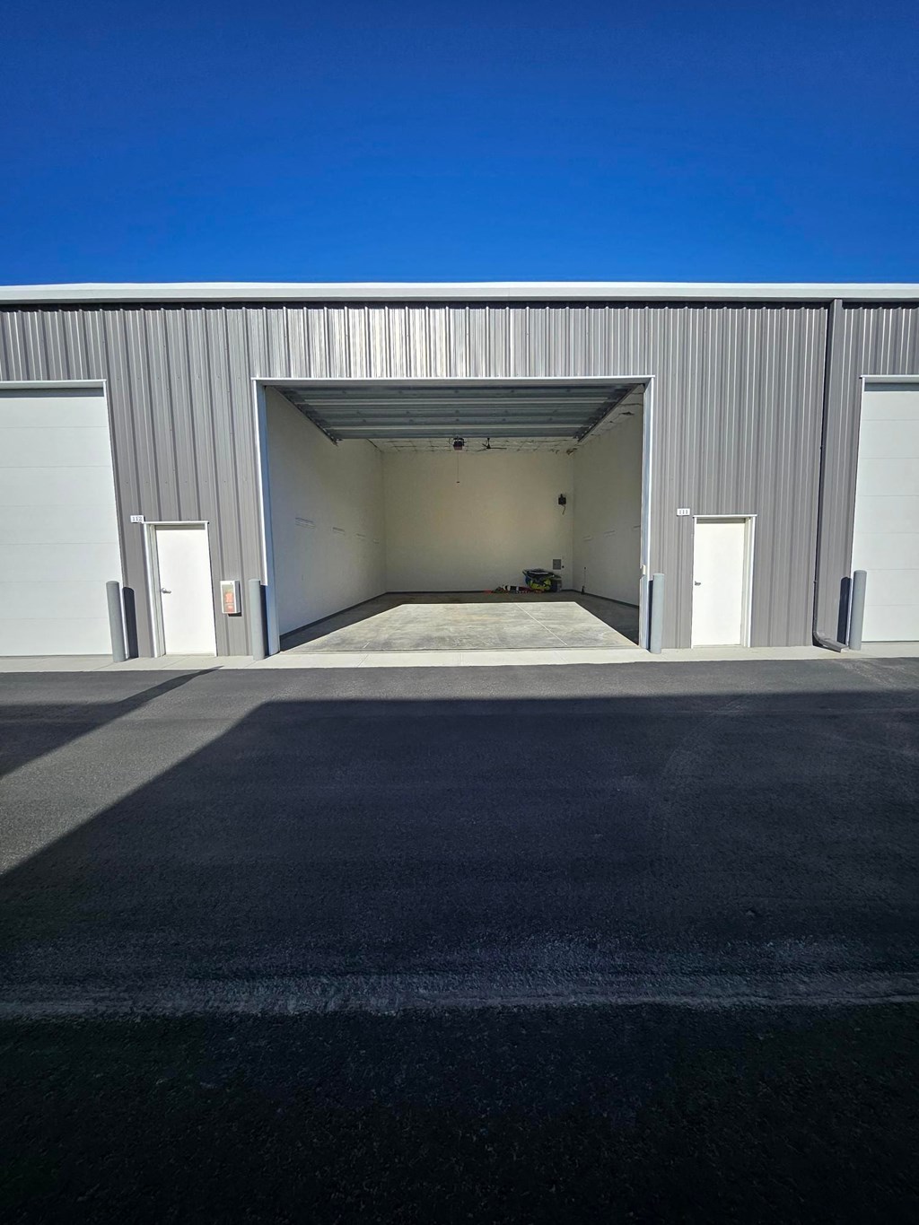 A large industrial building with a wide open garage door.
