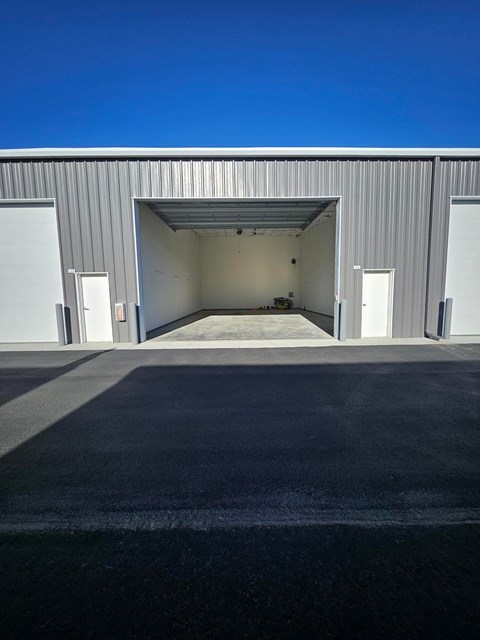 A large industrial building with a wide open garage door.