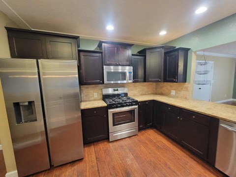 A kitchen with dark wood cabinets and stainless steel appliances.