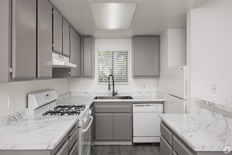 A kitchen with a white stove top oven and a white dishwasher.