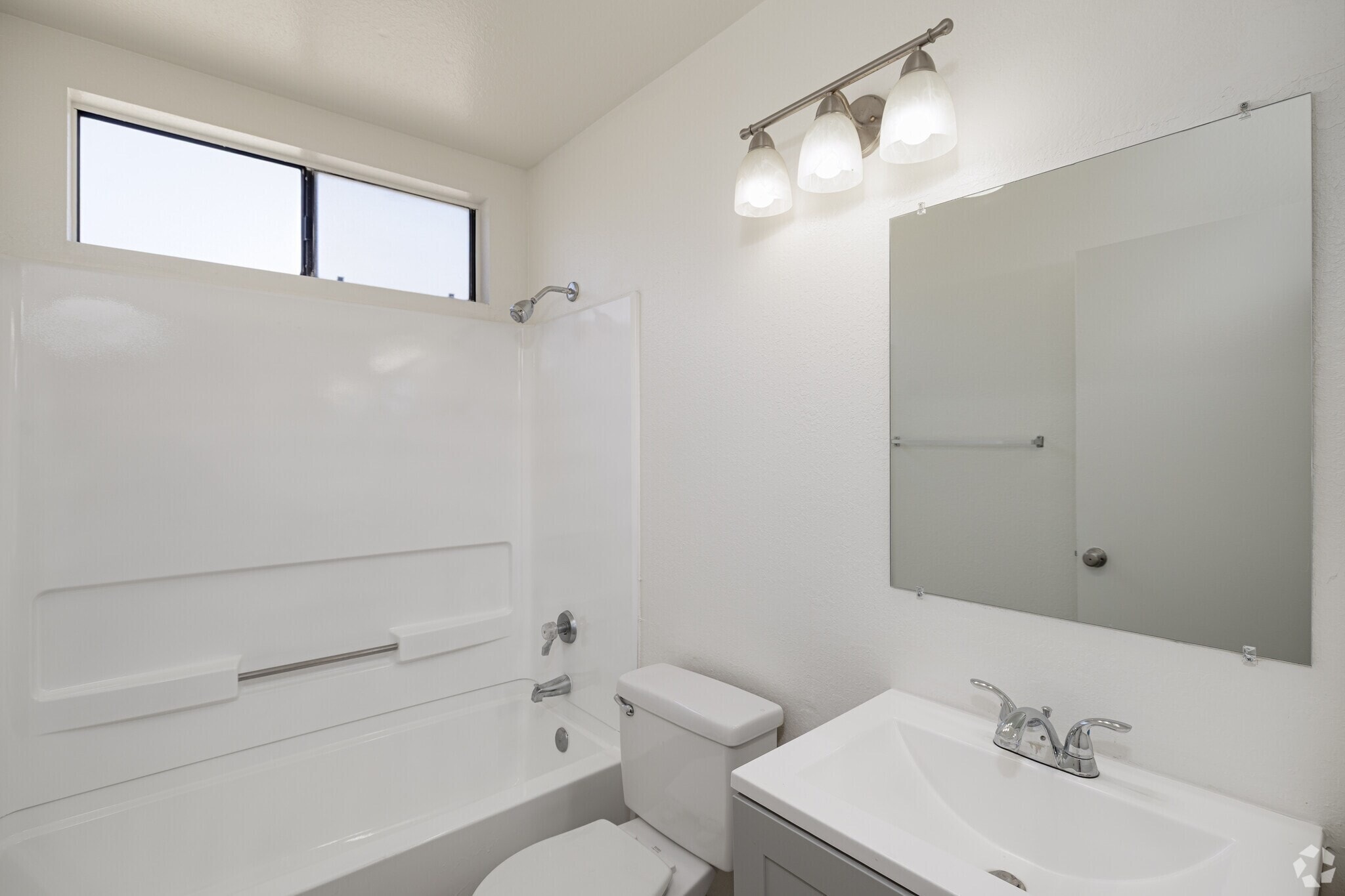 A white bathroom with a toilet, sink, and bathtub.