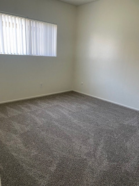 A room with a carpeted floor and a window with blinds.