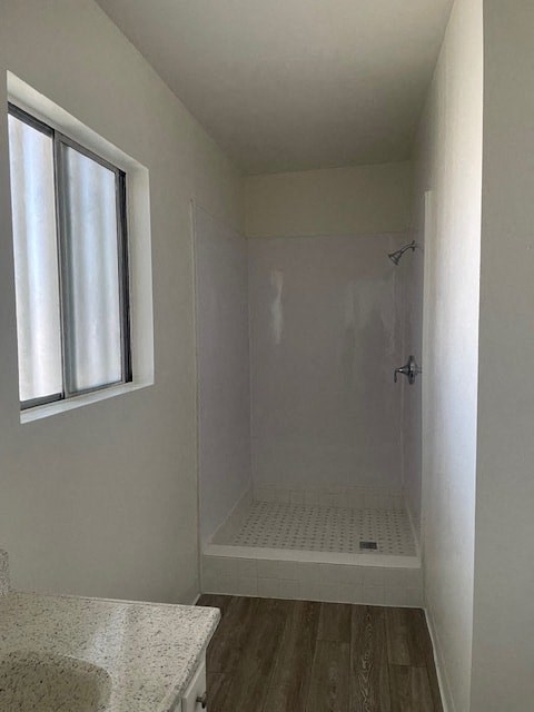 A white bathroom with a window and a walk-in shower.