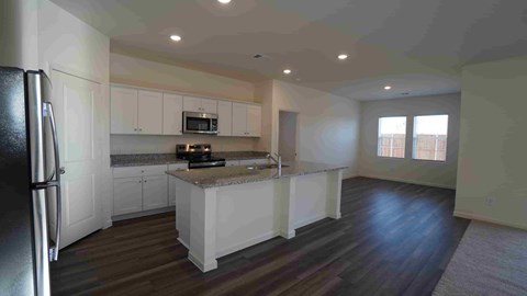 A kitchen with a refrigerator, microwave, and oven.