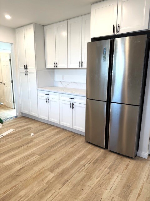 A kitchen with white cabinets and a stainless steel refrigerator.