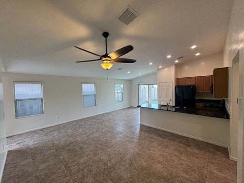 A spacious living room with a ceiling fan and a flat screen TV.