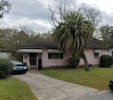 A pink house with a car parked in front.