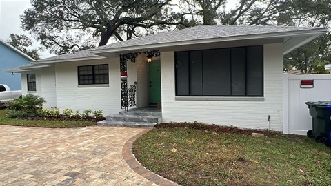 A white house with a green door and a red and white sign on the front door.
