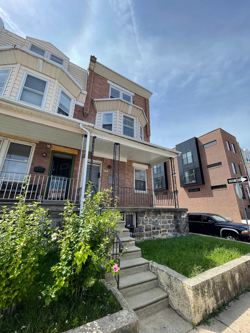 A row of houses with a black car parked in front of the last one.