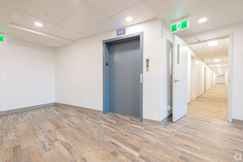 A hallway with a blue door and a green exit sign above it.