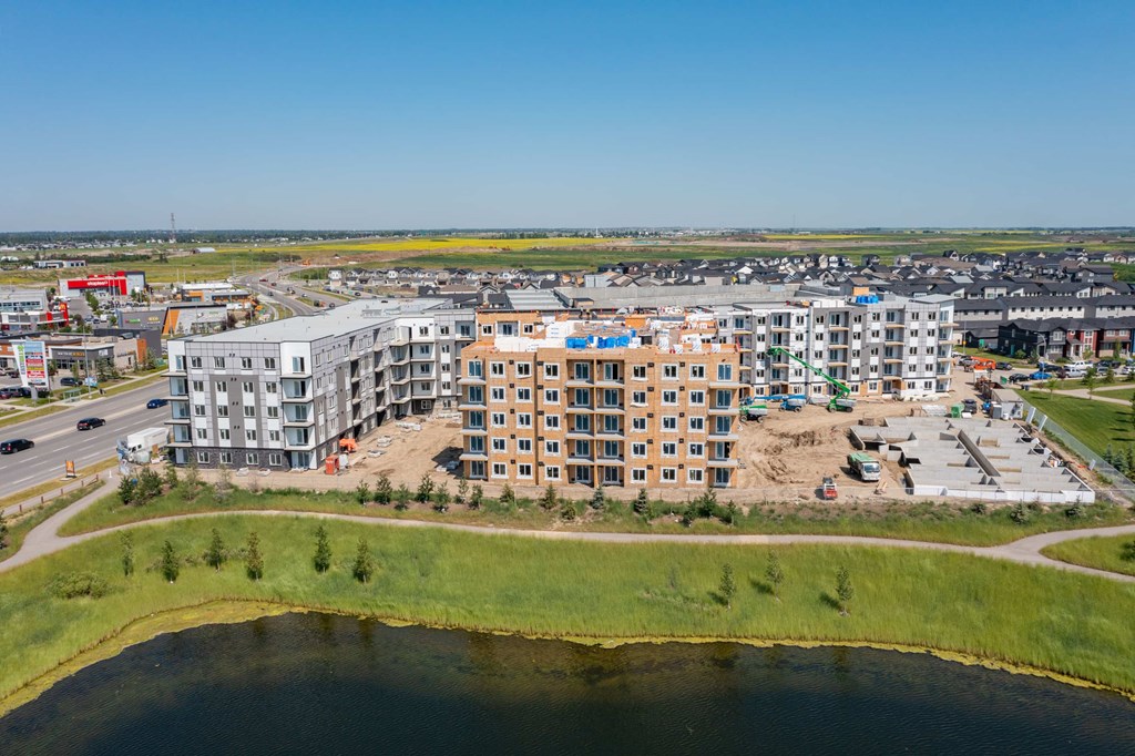 A large building complex with a parking lot in front and a body of water in the foreground.