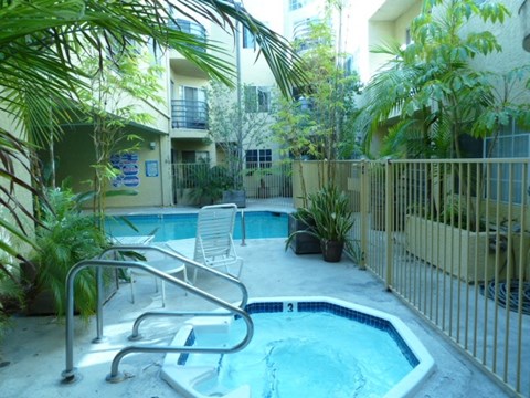 A small pool surrounded by a metal fence and a chair.