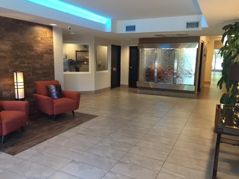 A hallway with a red chair and a plant on the right side.