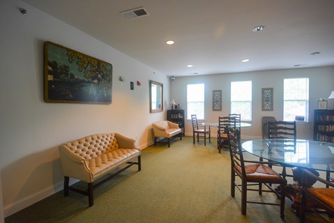 A living room with a sofa, chairs, and a painting on the wall.