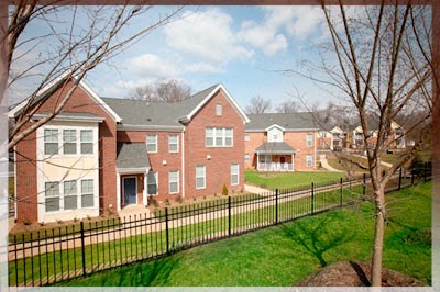 A red brick house with a black fence in front.