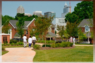 A group of people walking on a sidewalk in a park.