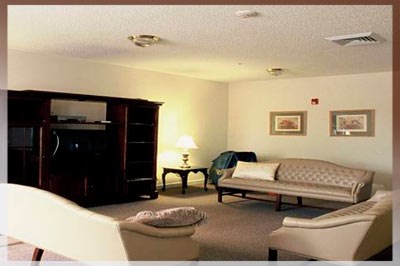 A living room with a couch, chair, ottoman, and lamp.