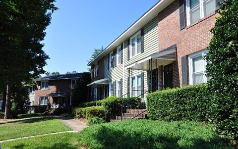 A residential building with a red brick facade and a green lawn in front.
