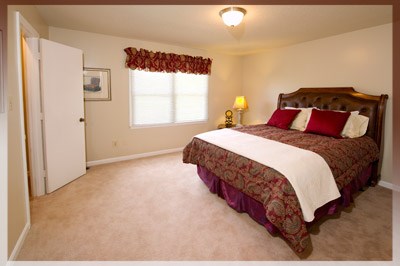 A bedroom with a large bed and a window with red curtains.