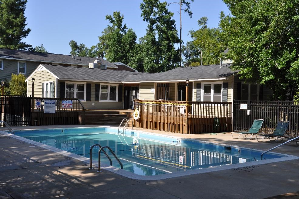 A pool in front of a house with a fence around it.