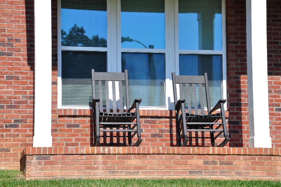 Two chairs are placed on the windowsill of a brick house.