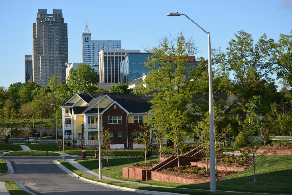 A street view of a residential area with apartment buildings and trees.
