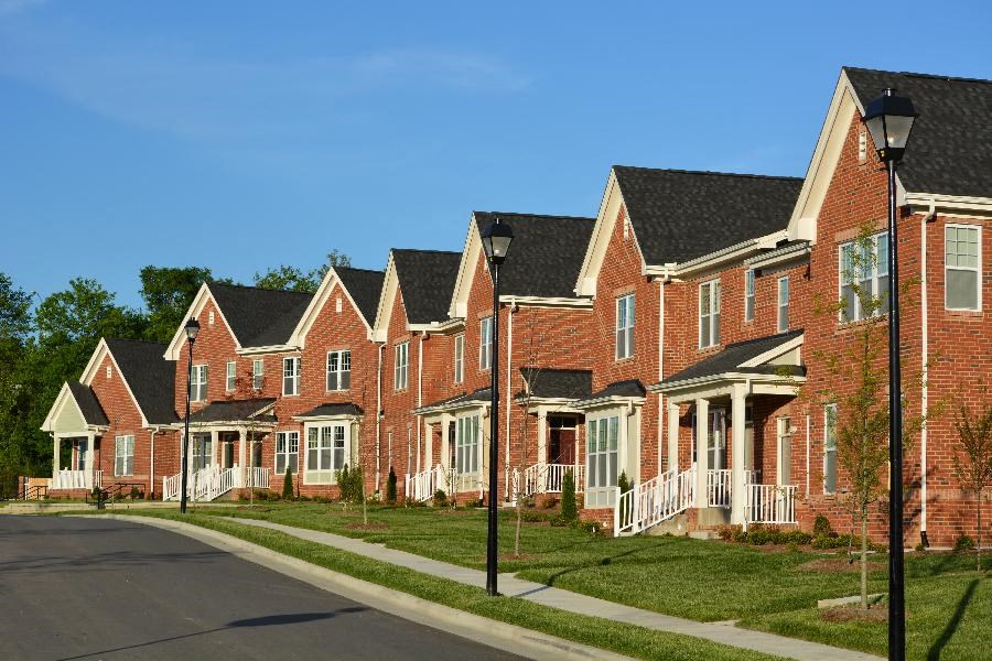 A row of red brick houses with white trim and black roofs.