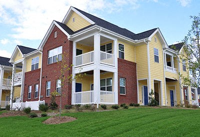 A yellow and red two story apartment building with a balcony on the second floor.