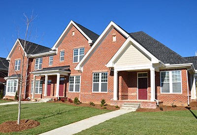 A red brick house with a white trim and a small tree in front.