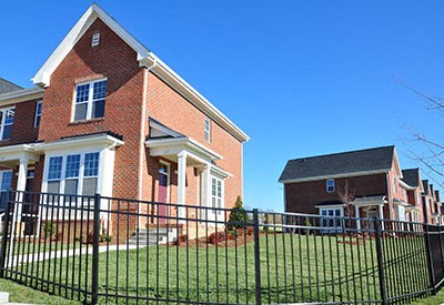 A large red brick house with a black fence in front.
