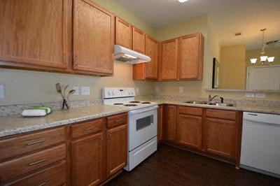 A kitchen with wooden cabinets and a white stove top oven.