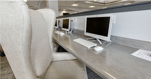 A white chair is positioned in front of a desk with a computer monitor and keyboard.