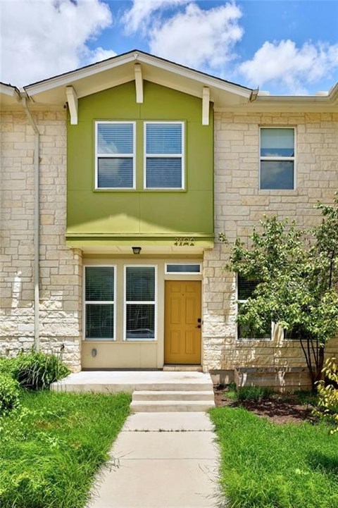 A green house with a brown door and a small porch.
