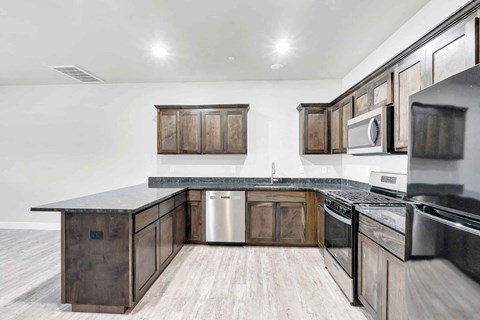 A modern kitchen with dark wood cabinets and stainless steel appliances.