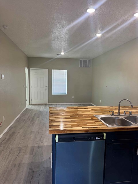 A kitchen with a wooden counter top and a dishwasher.