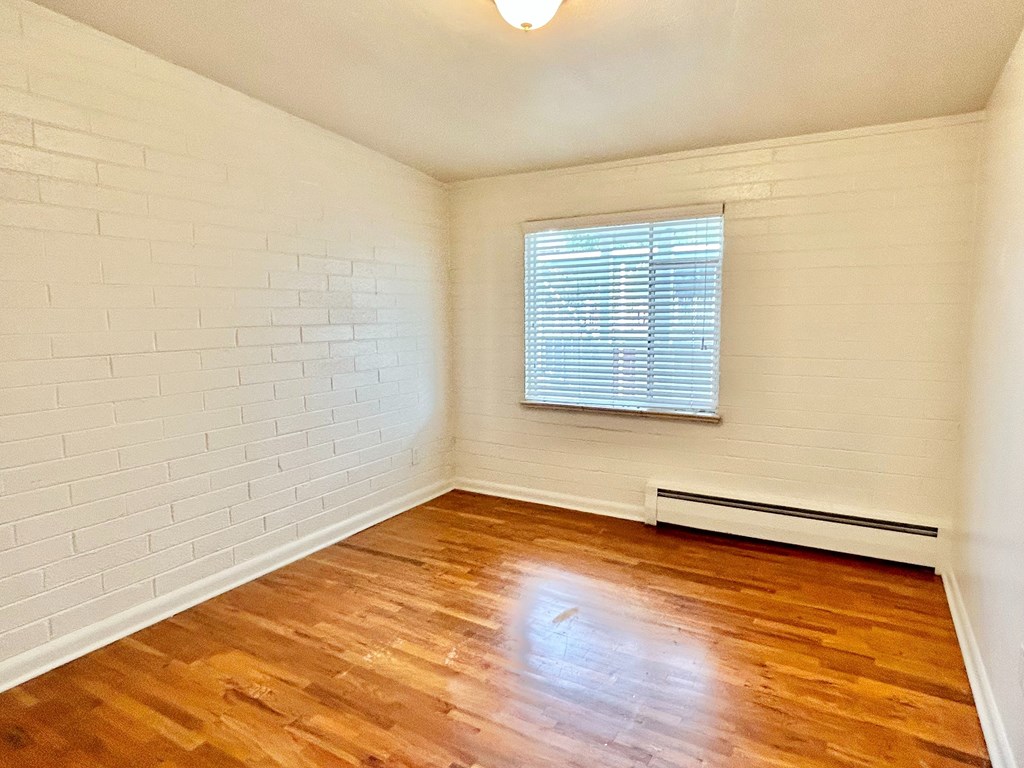 A room with wooden floors and white brick walls.