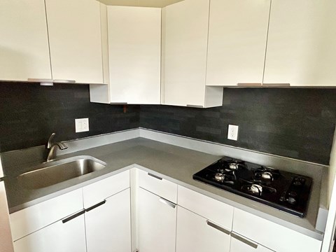 A kitchen with white cabinets and a black countertop.