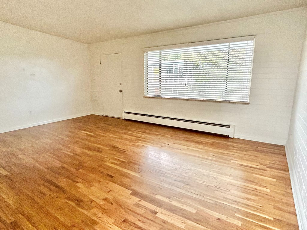 A room with wooden flooring and a window with blinds.