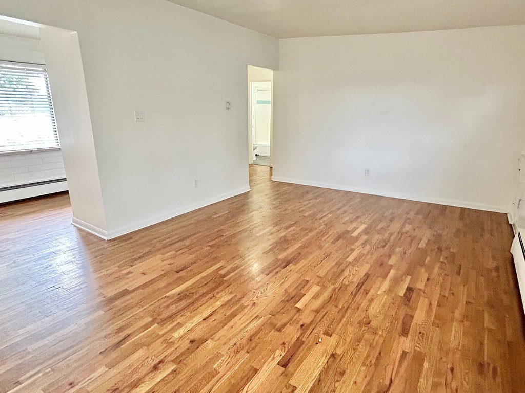 A room with wooden flooring and white walls.