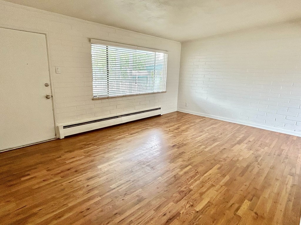 A room with wooden flooring and a window with blinds.